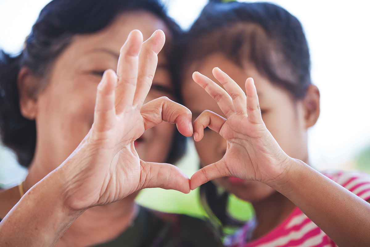Mother and daughter making heart symbol with their hands