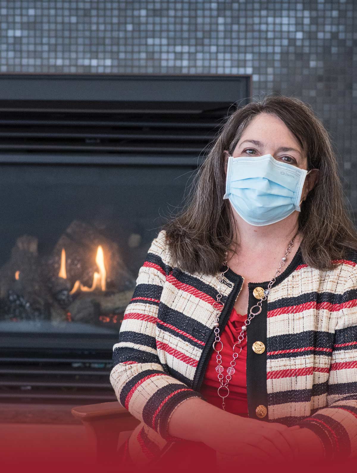 Shelley Ebenal sitting in front of a fireplace with a medical mask on