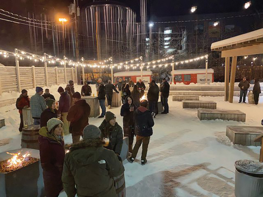 crowd enjoying outdoor drinks in the snow with overhead string lights
