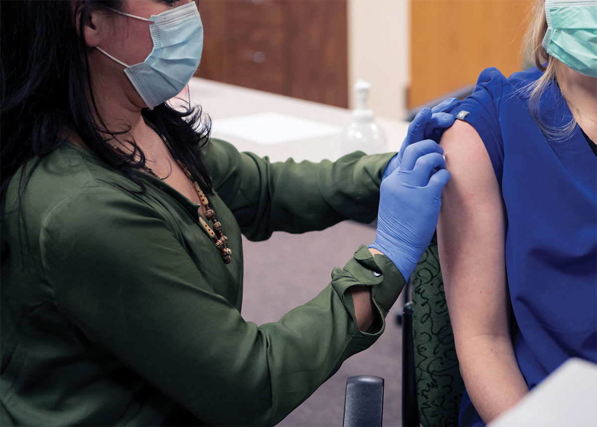 Registered Nurse Nicole Vosgien, with Providence Kodiak Island Medical Center’s Caregiver Health Services, administers the COVID-19 vaccine to Dr. Dana Kerr