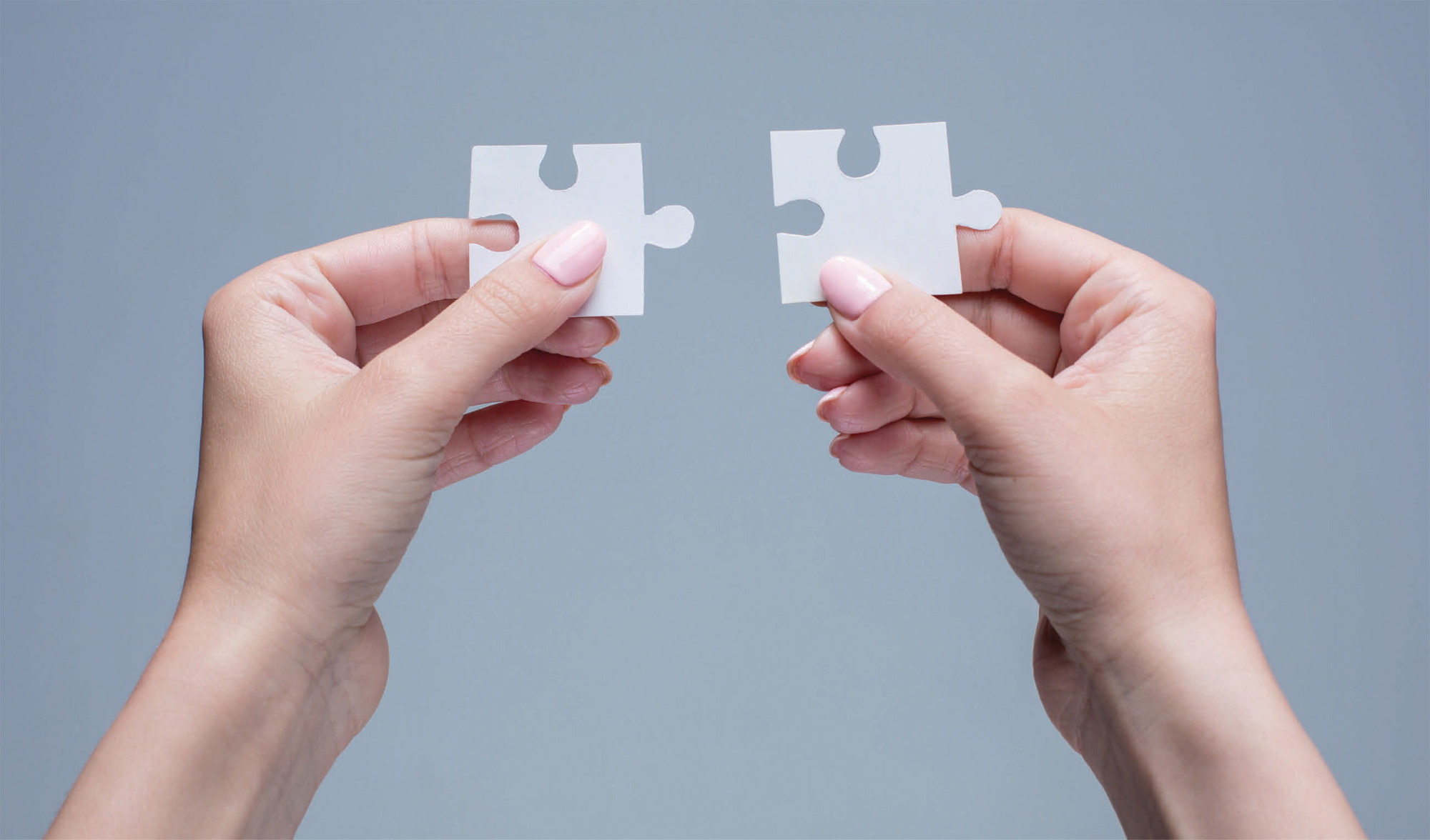 woman's hands hold two puzzle pieces close together
