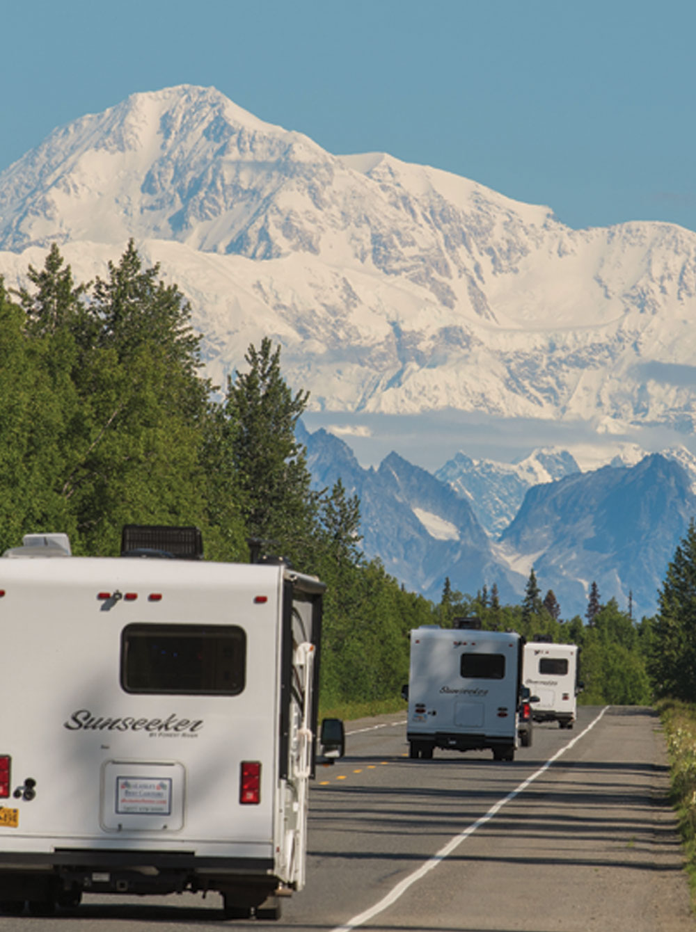 RVs driving toward a large snow covered peaks