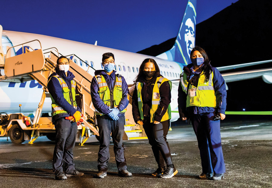 Four Alaska Airlines employees in front of airplane
