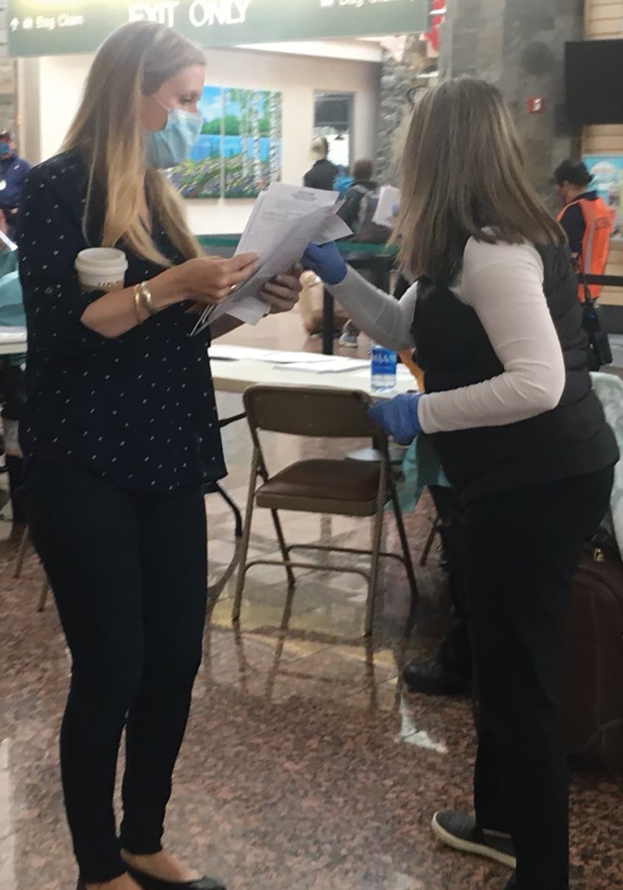 healthcare worker assisting a traveler with paperwork at Ted Stevens Anchorage International Airport