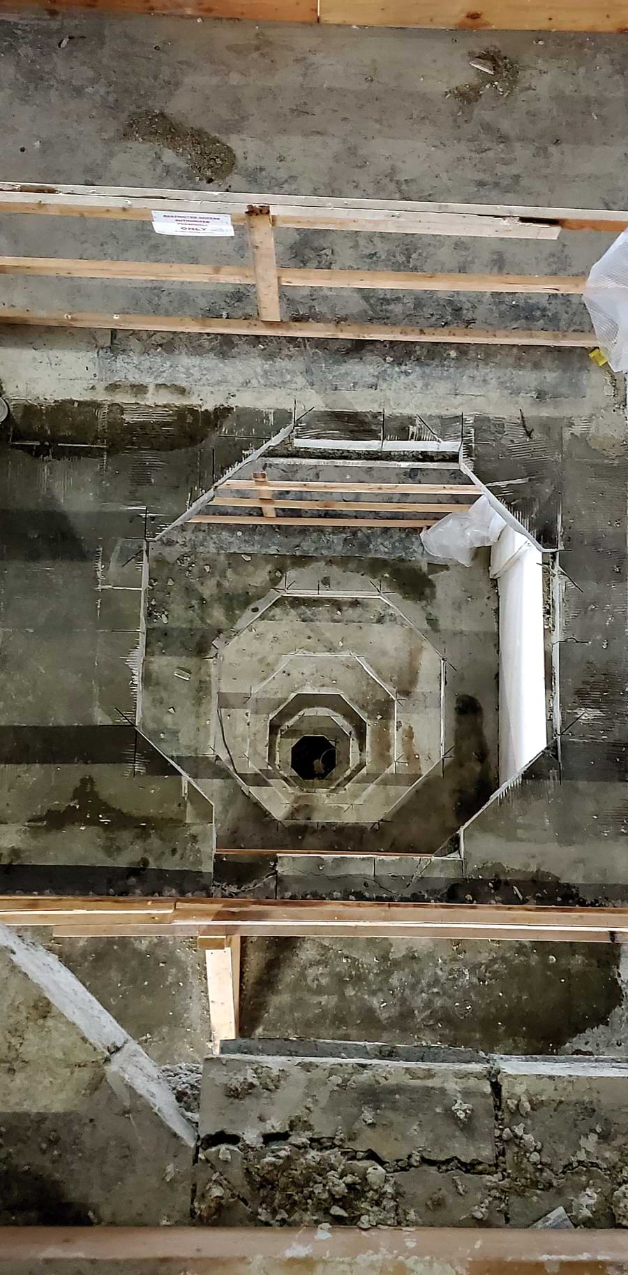 Looking down between the two core elevators, a wider rising air duct is being installed to service the enlarged interior volume.