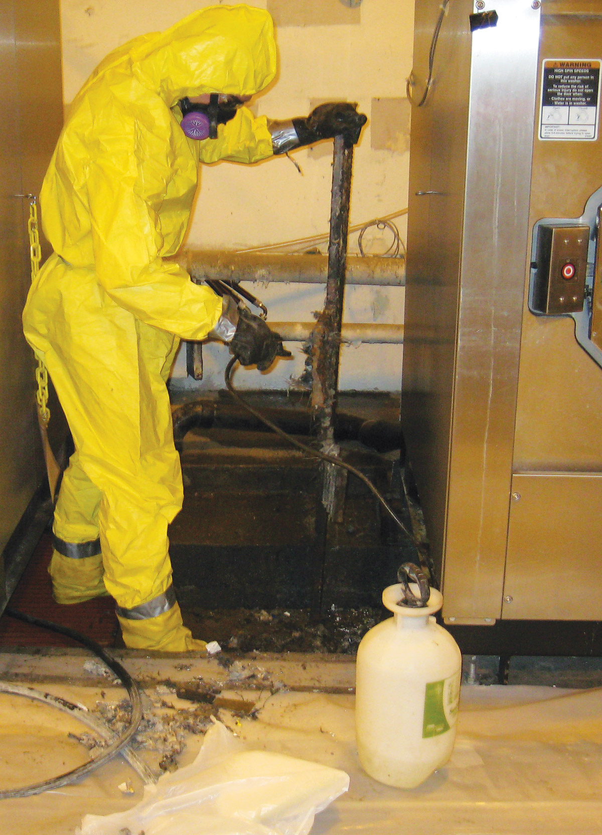 worker in hazmat suit spraying liquid