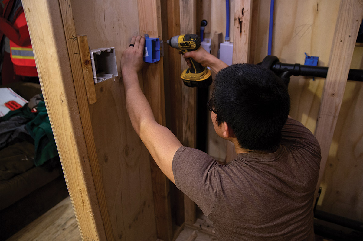 An ANTHC worker installs electrical wiring and indoor plumbing in a house