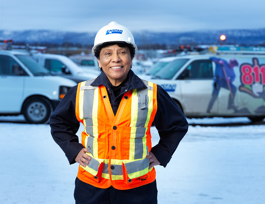 Enstar employee out in a parking lot wearing a orange work vest