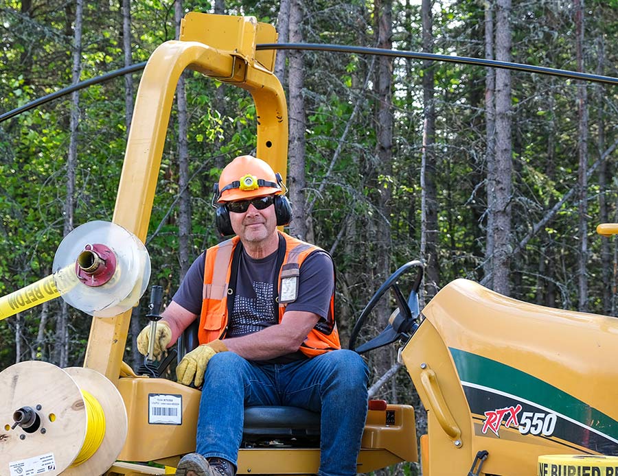 Enstar employee sitting on his large machinery with a hardhat on