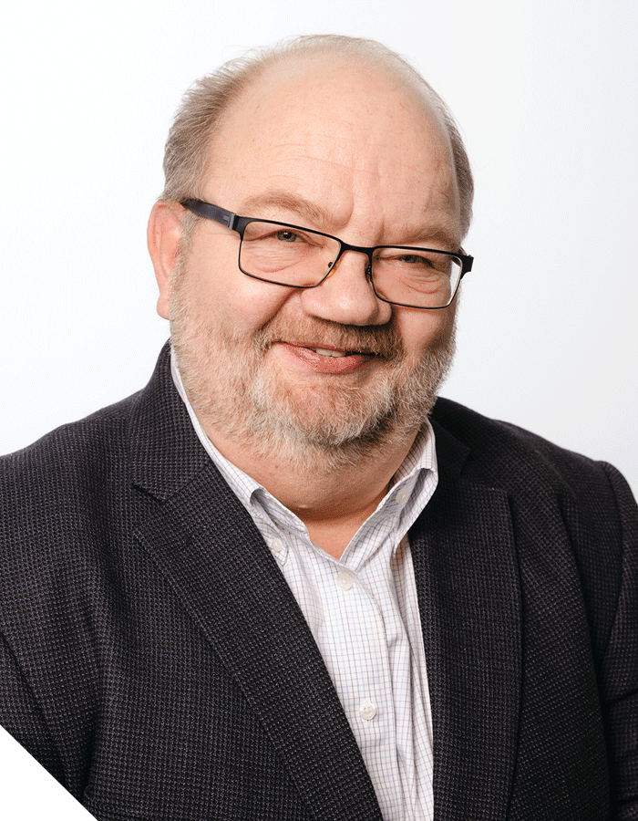 Janis J. Plume smiling in a suit against a white background