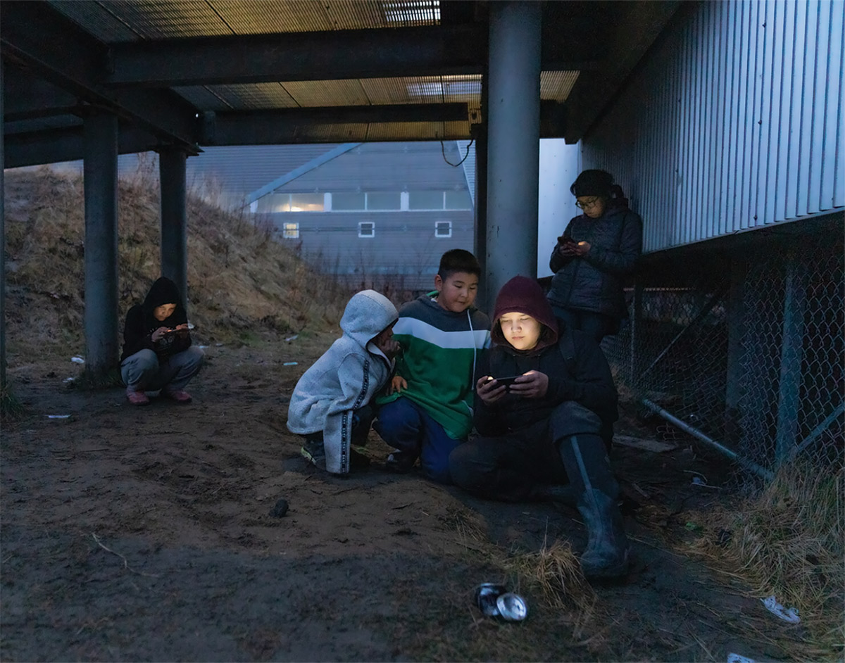 Kids hang out near the school in Akiak to access wireless internet through their phones
