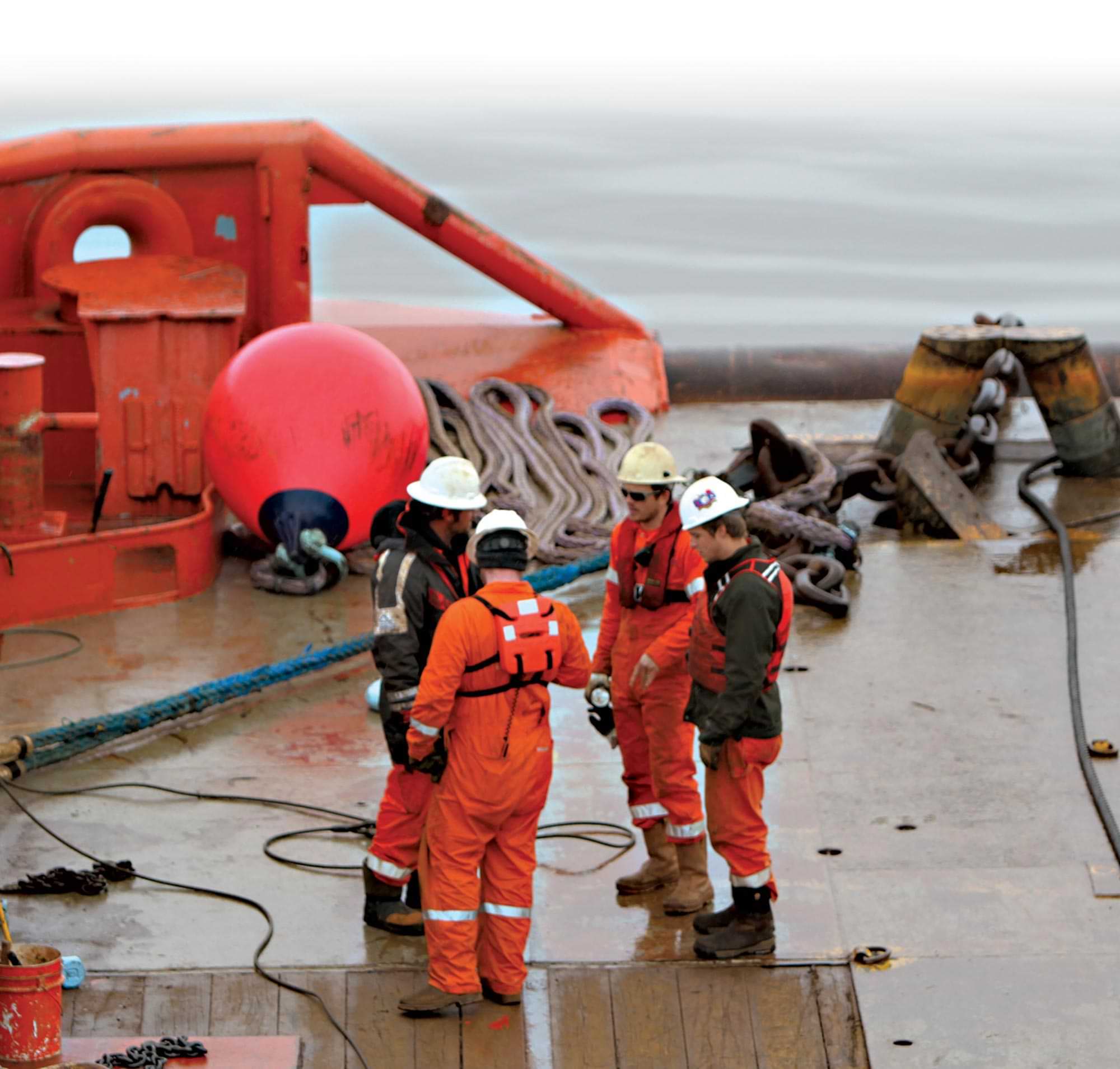 men stand on an industrial platform wearing safety gear