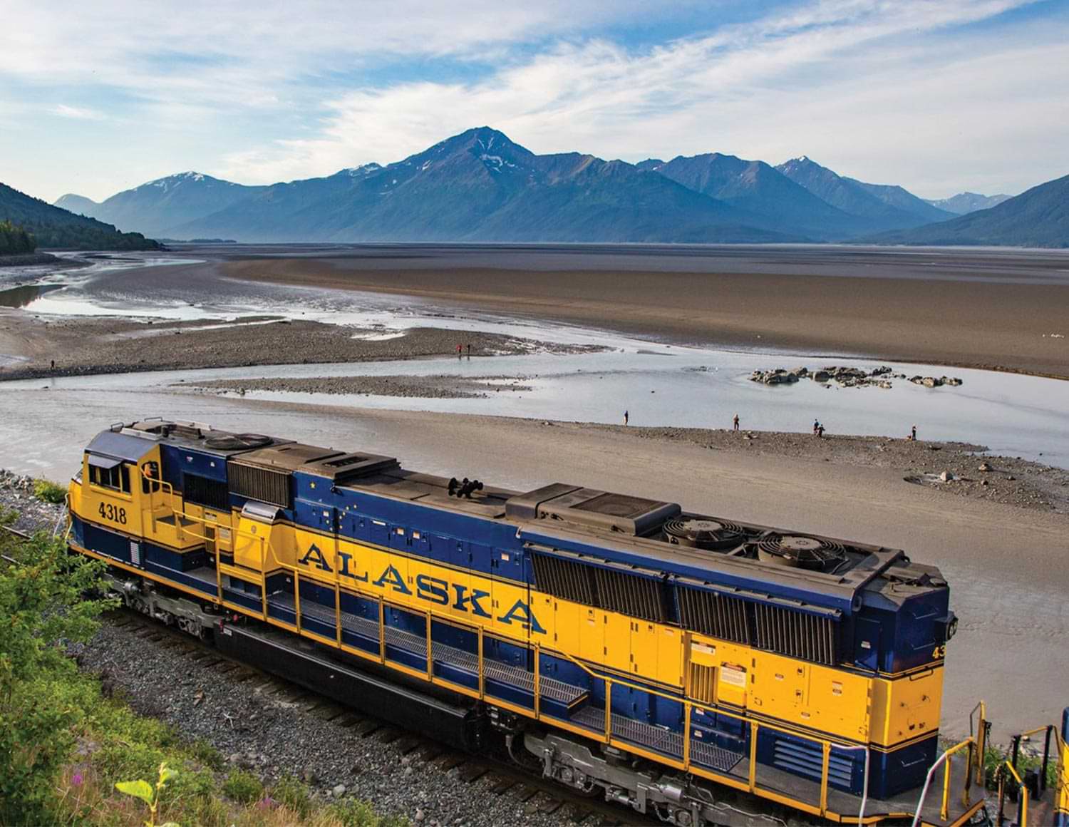 an Alaska Railroad train travels tracks by a beach like area