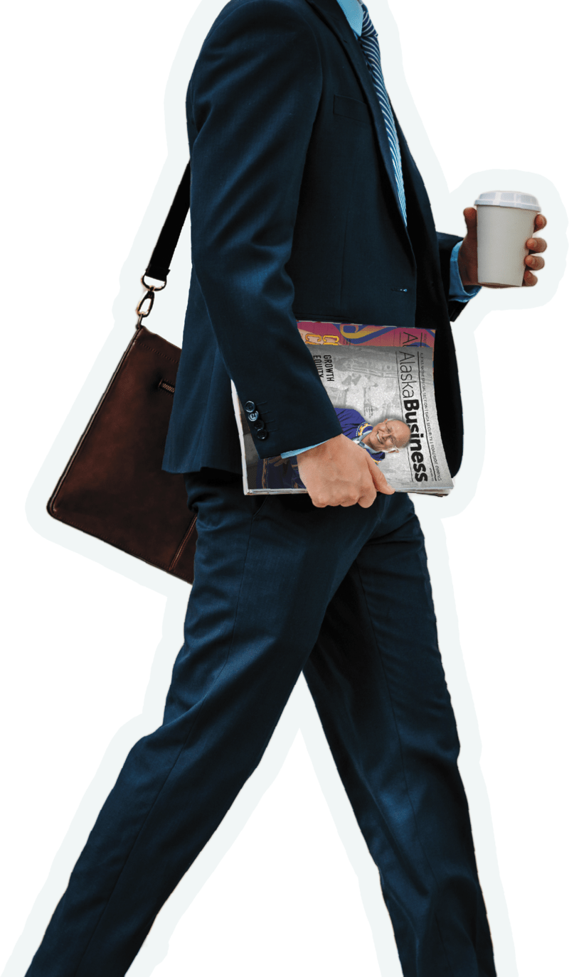 Man walking holding coffee cup in one hand and Alaska Business magazines in the other