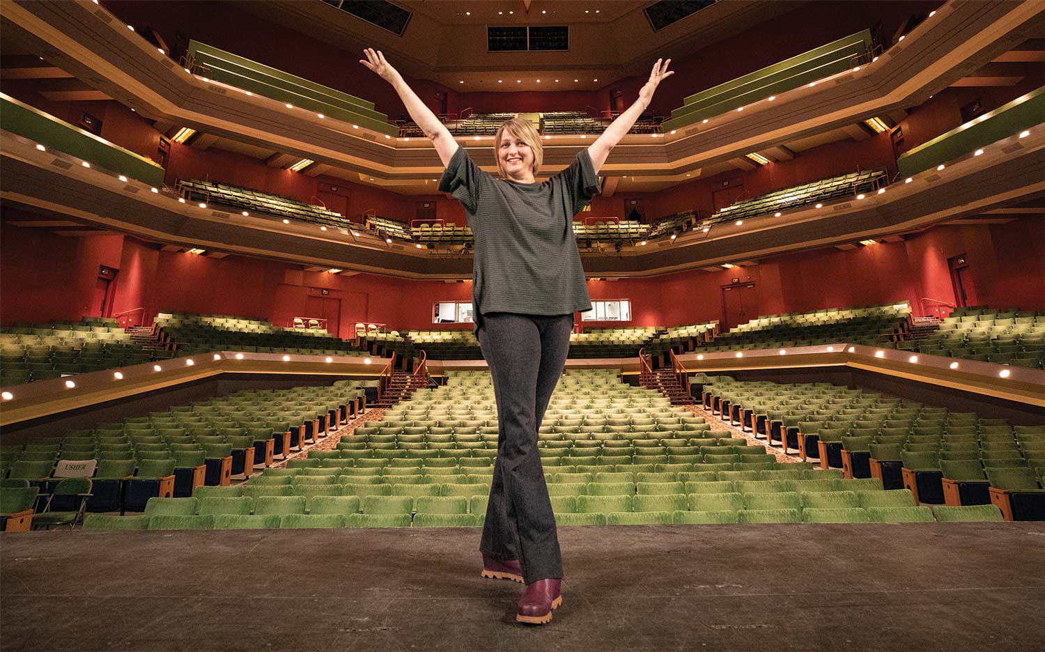 Codie Costello with arms raised on stage in Alaska Center for Performing Arts
