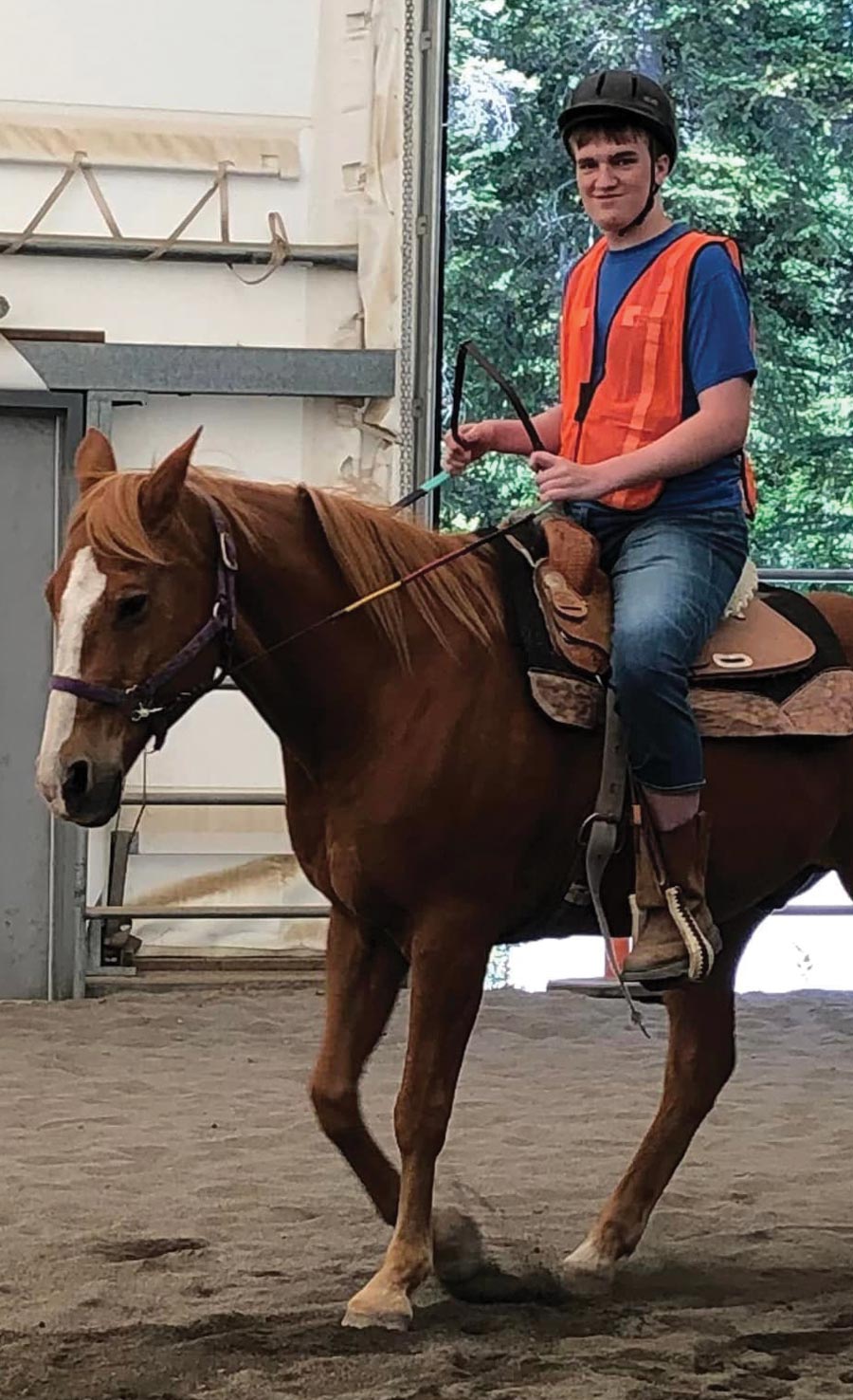 man in orange vest riding horse