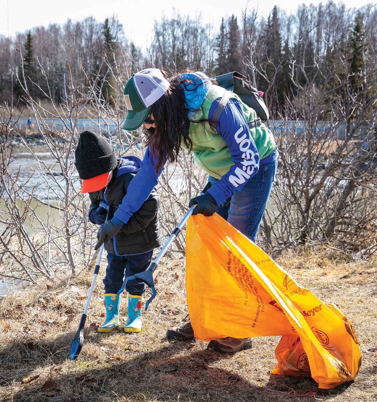 woman picking up litter with child
