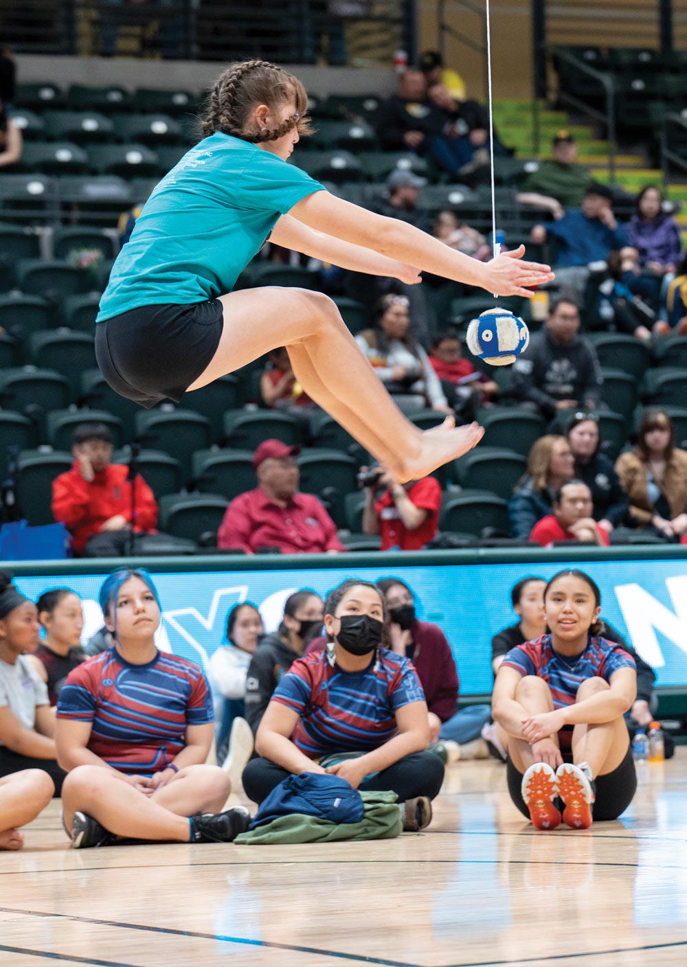 a girl pictured in mid-air during a play at the Native Youth Olympics