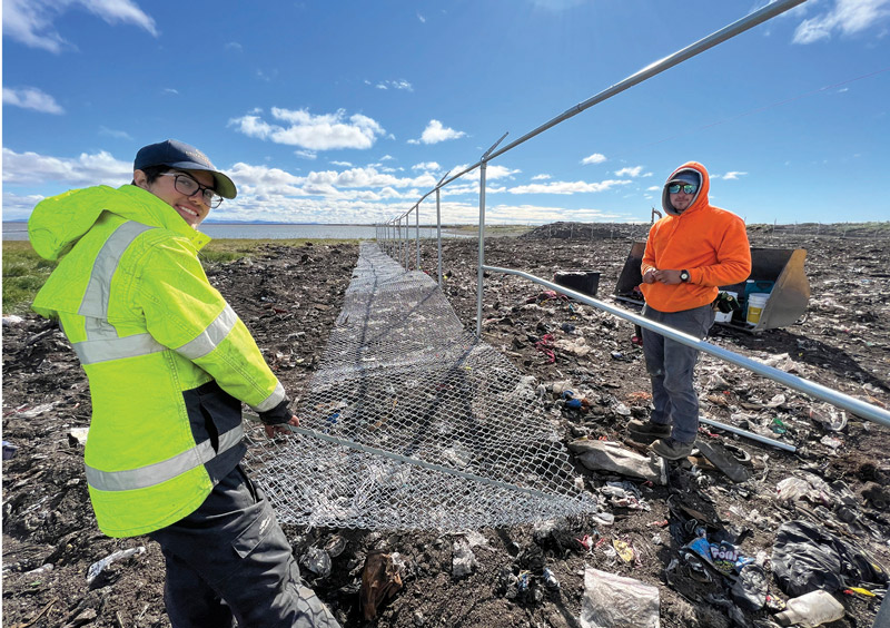 Workers attaching chainlink to planted fence poles