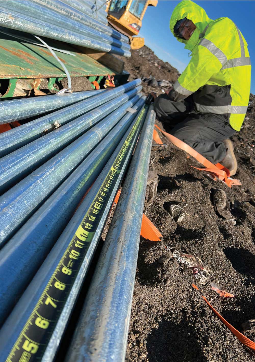 Worker measuring pipe lengths for fence