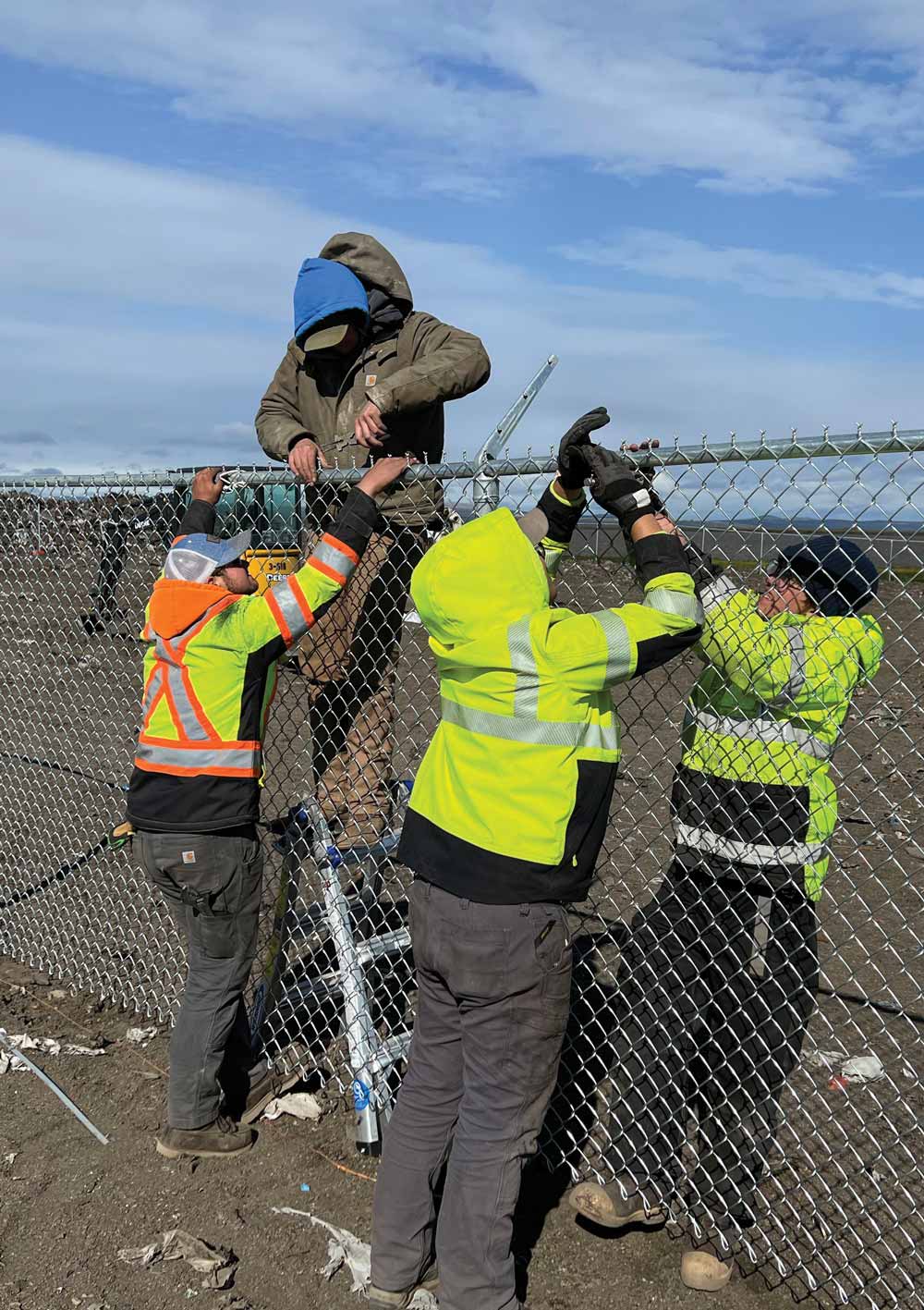 Workers installing new fenced along landfill edges