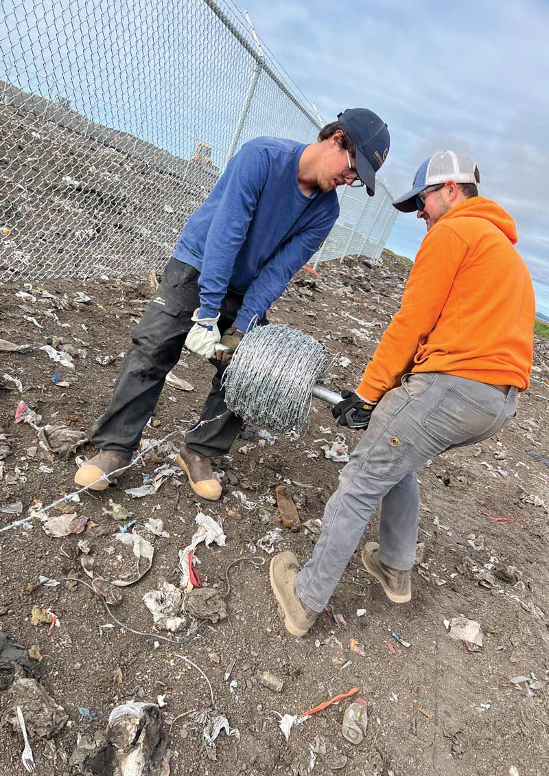 Workers rolling out spool of barbed wire