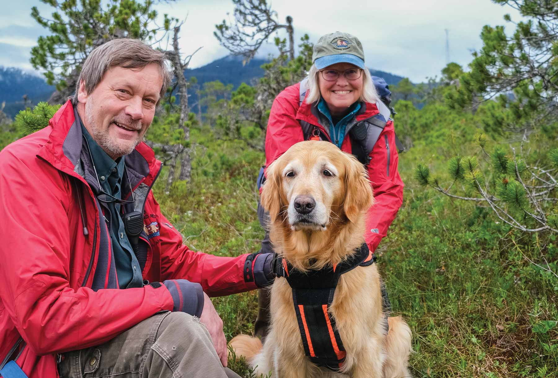 Geoff and Marcy Larson with their dog Tango in a grassy opening
