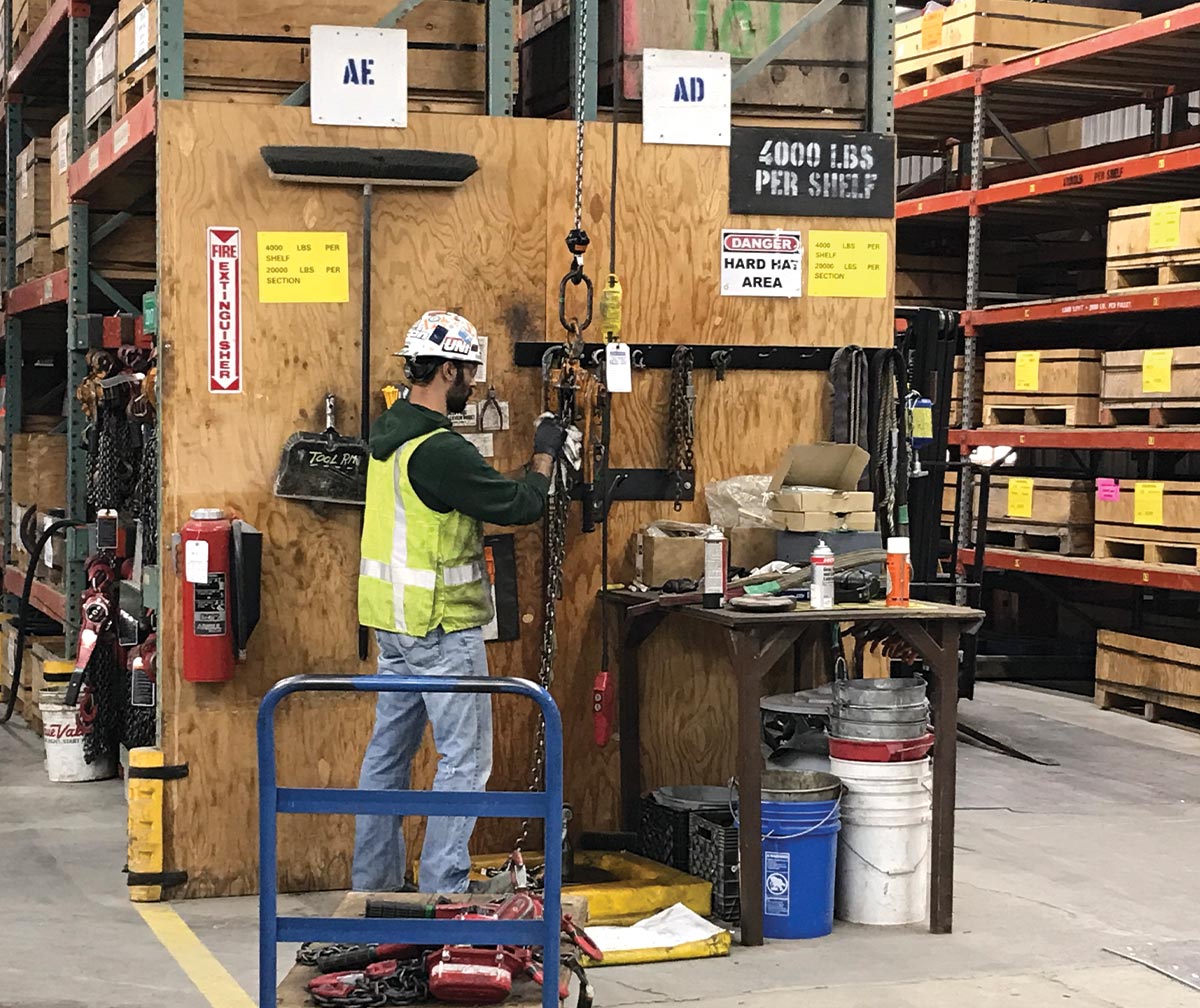 Man in hard hat and construction vest working with chains