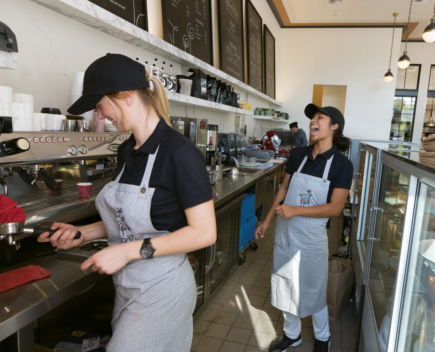 2 baristas laughing and having fun at work