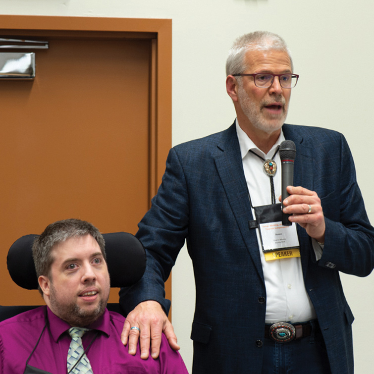 man speaking into microphone next to another person