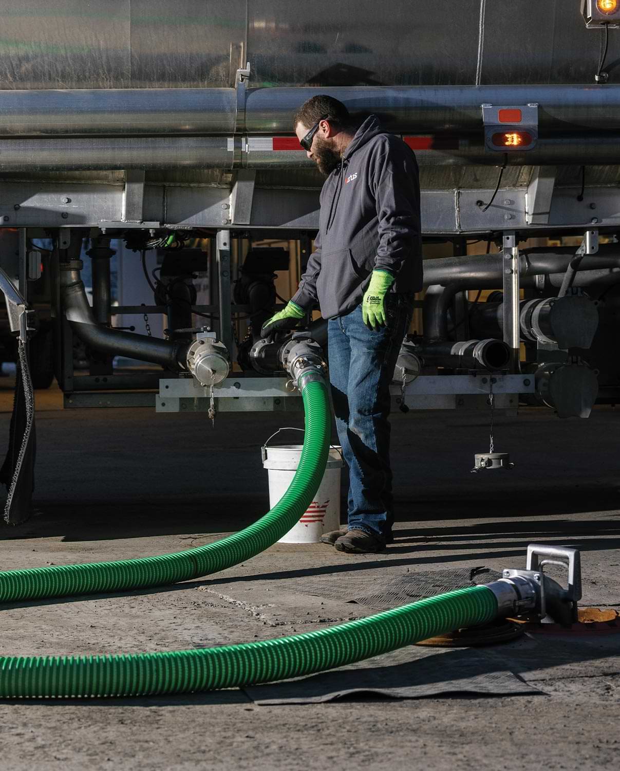 a fuel truck operator observes the hose end connected to the fuel truck during pumping
