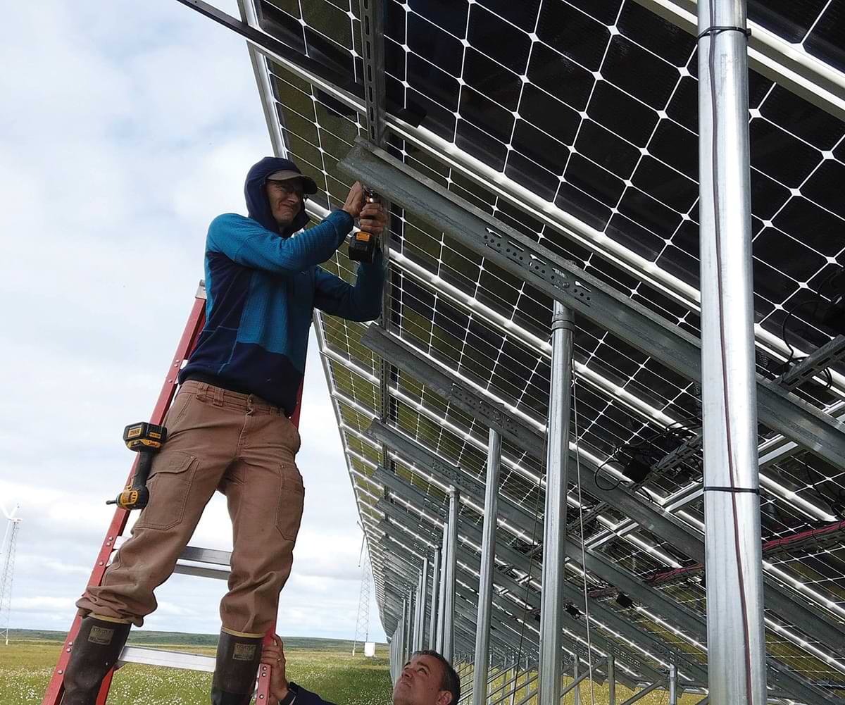 Alaska Center for Energy and Power’s Chris Pike installs a monitoring camera on a solar panel in Kotzebue, 30 miles north of the Arctic Circle. The solar panel is part of the 576kW bifacial array owned and managed by Kotzebue Electric Association.