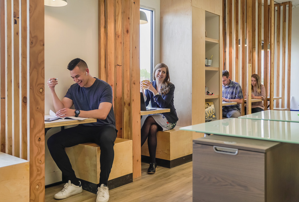 4 people sitting in individual seating made of assorted wood, reading and smiling