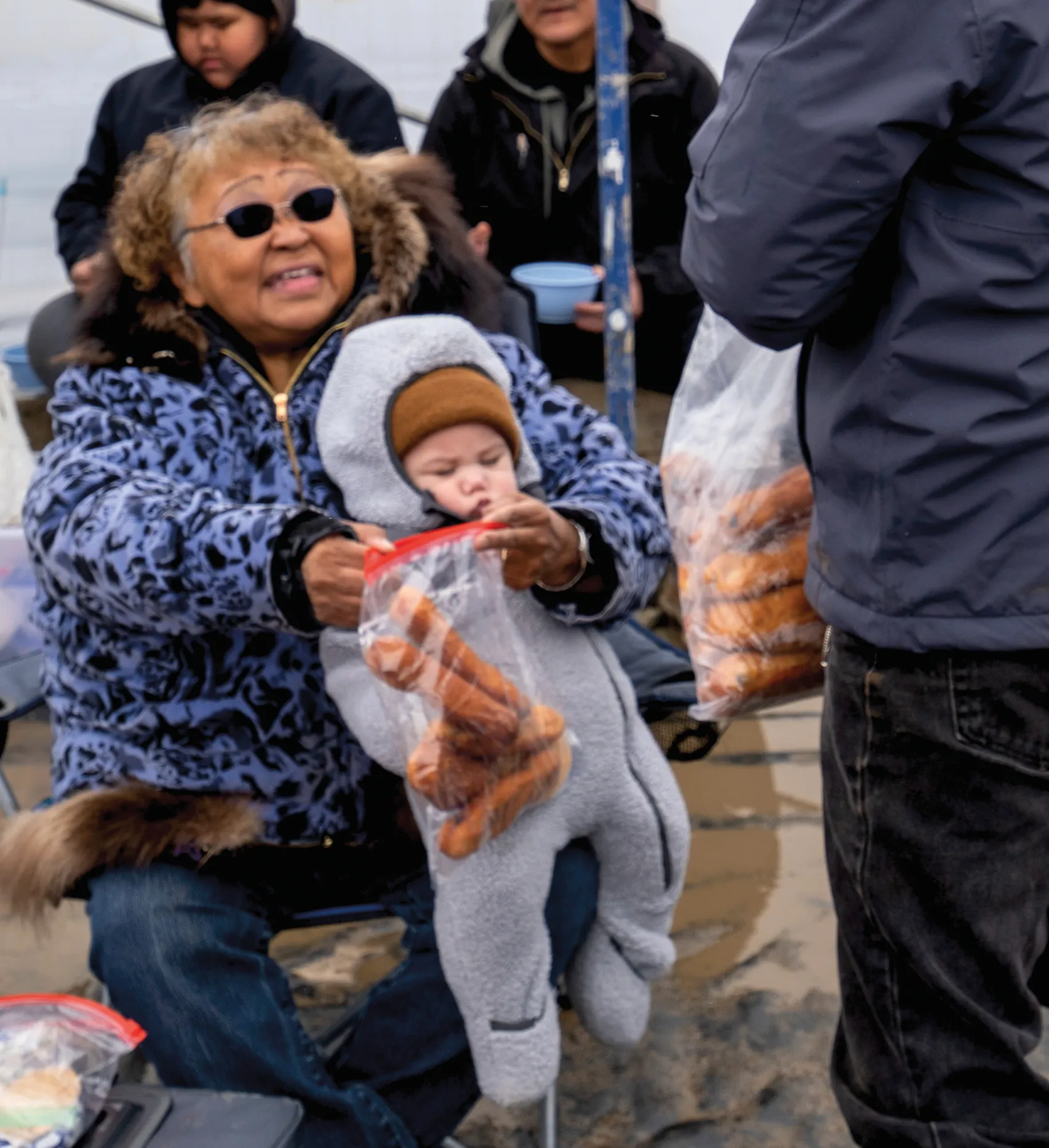 Woman holding baby and food in plastic bags