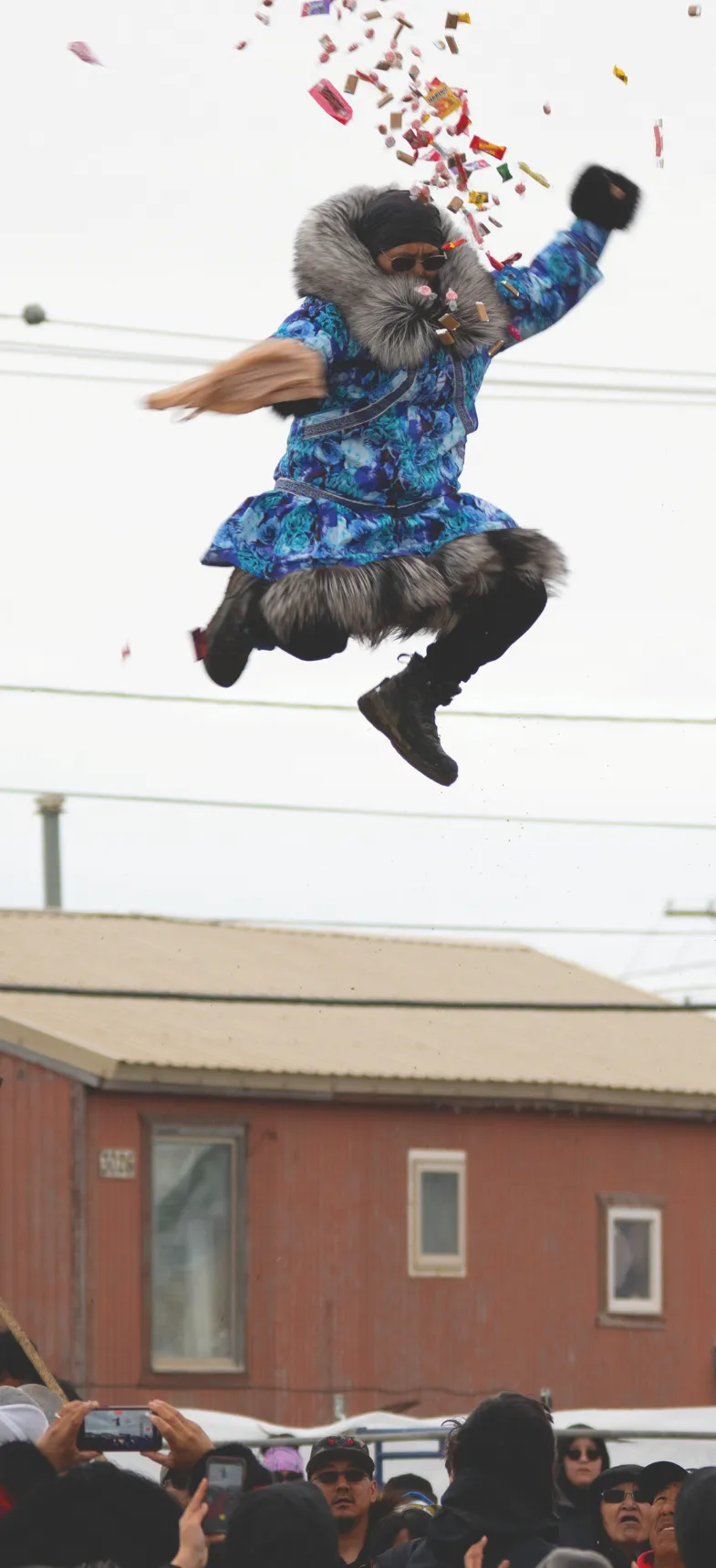 Person in bright blue jacket jumping through the air