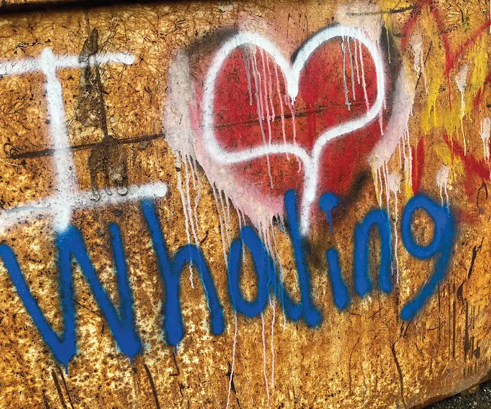 Wooden sign with "I heart whaling" written in white, red and blue spray paint