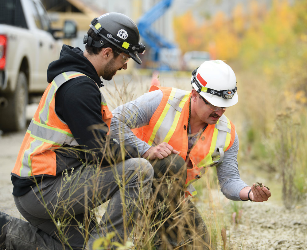 2 construction workers looking at soil