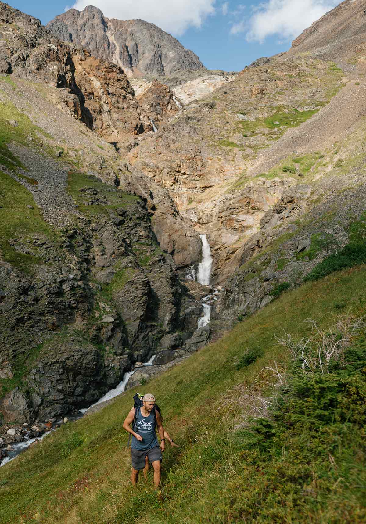 Portrait photograph of two hikers on Crow Pass trail on a sunny day; Crow Pass trail takes hikers above treeline. The trailhead is off Crow Creek Road in Girdwood.