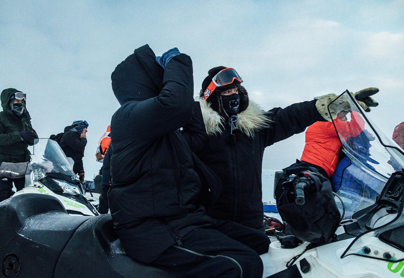 a bear guard working for UIC Science, all dressed in puffy coats, goggle and face masks and riding ATVs, helps a field research team