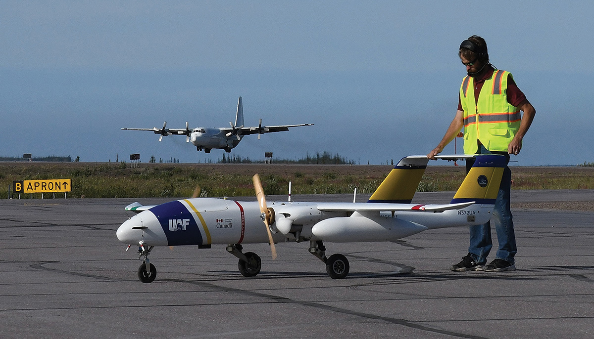 SeaHunter on runway, with man in yellow vest inspecting the drone