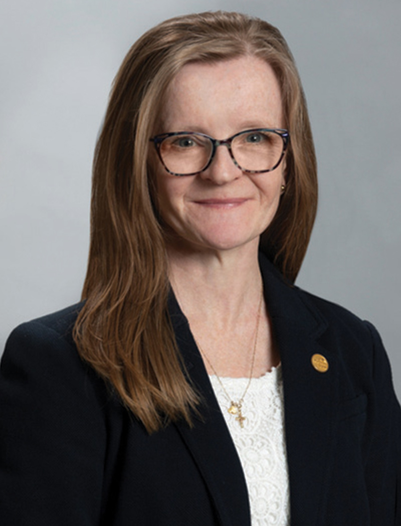 Headshot of a woman with brown hair, wearing glasses, a black blazer and white shirt (Nicole Johnson)