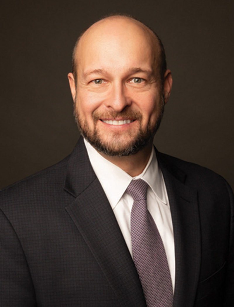 Headshot of a man wearing a black suit jacket, tie, and white shirt (Dan Graham)