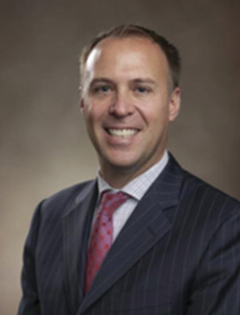 Headshot of a man wearing a striped suit jacket, red tie, and light shirt (Jonathan Dalrymple)