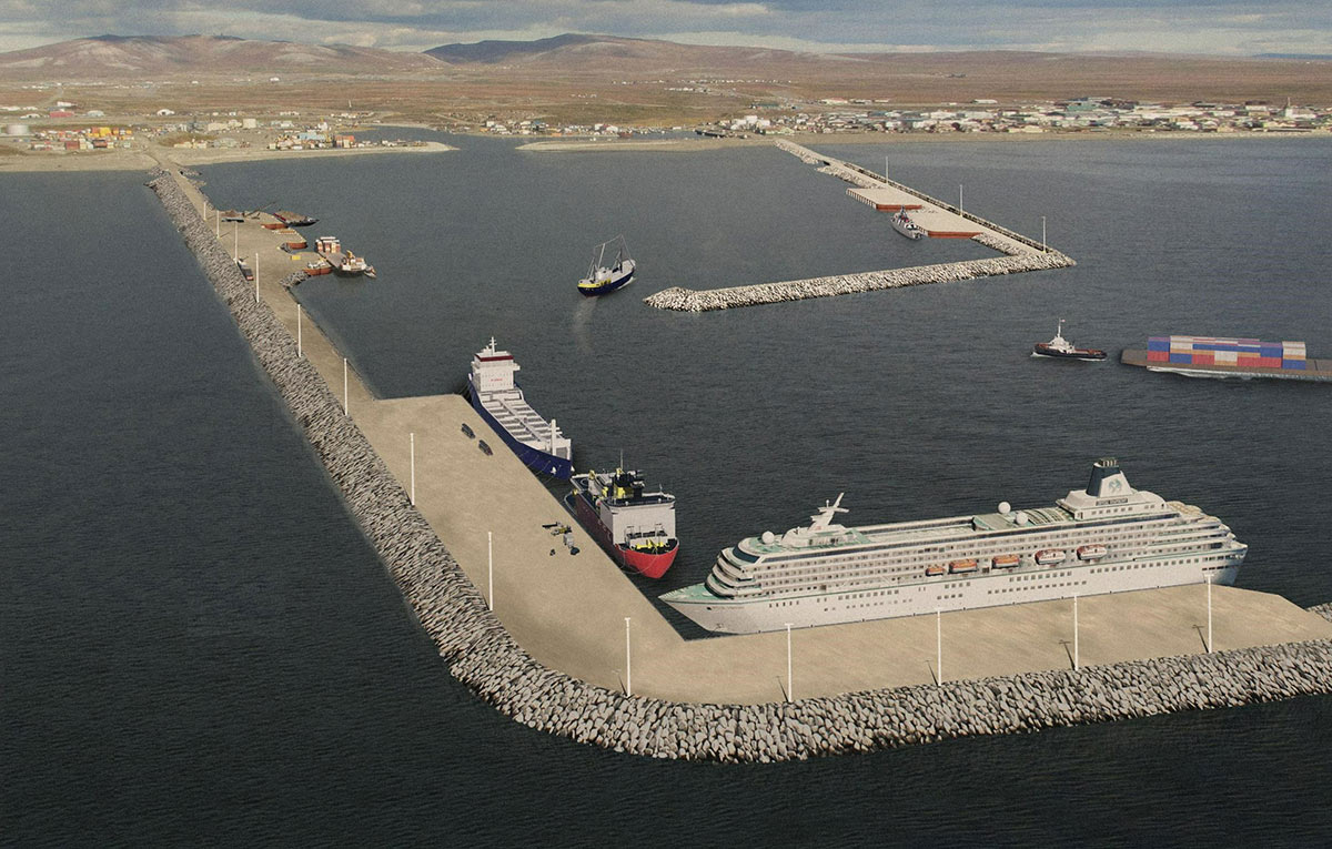 Aerial landscape photograph perspective of The Port of Nome in Nome, Alaska during the day with a few cargo ships and a cruise ship in the water within the foreground while the town of Nome is located on the land in the background