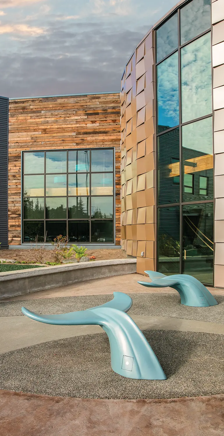 front view of the Kahtnuht’ana Duhdeldiht campus with a focus on whale tale shaped benches that architecturally reflect the importance of beluga whales to the Kenaitze Tribe