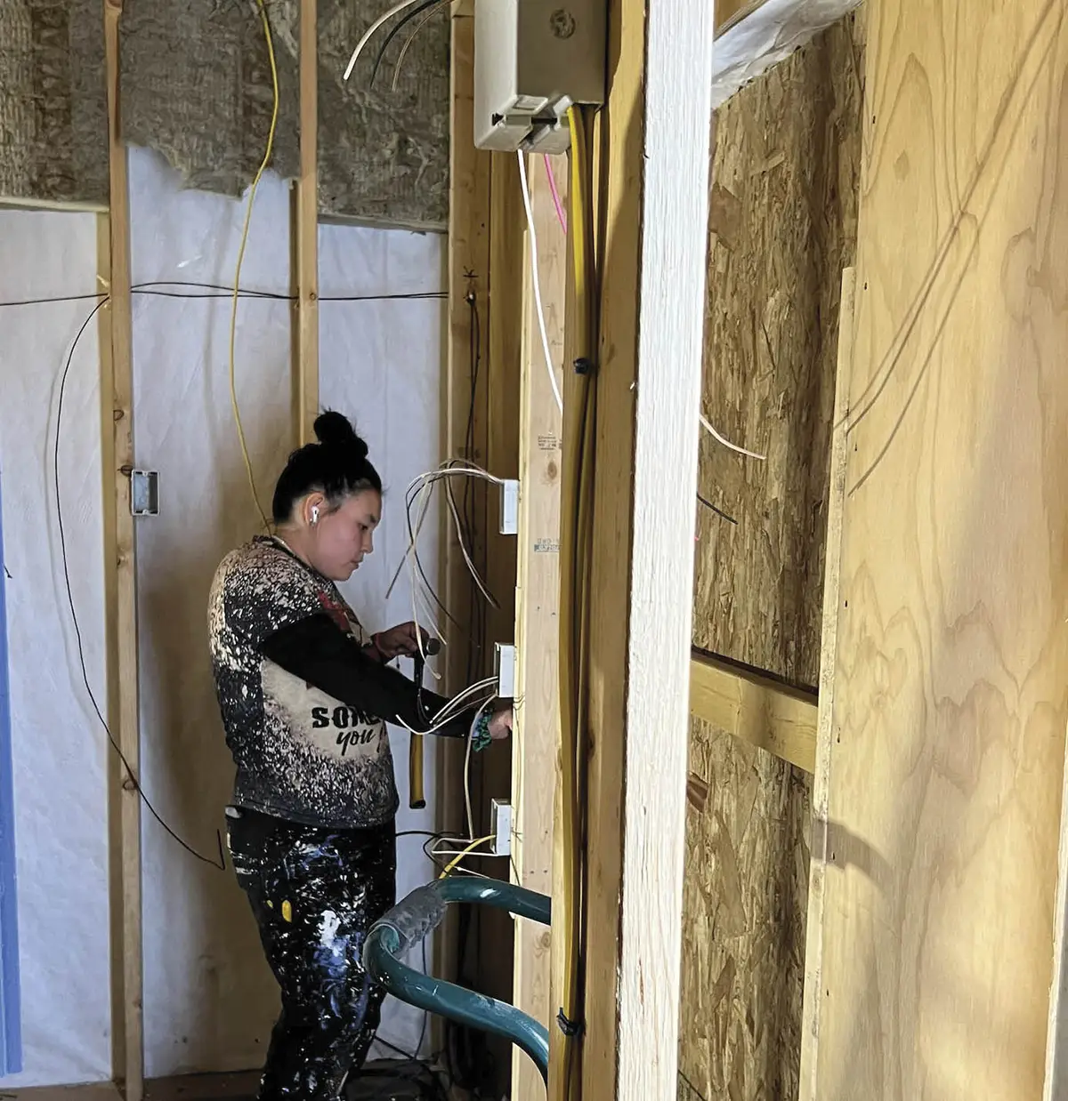 Point Lay resident Teri Ferreira secures electrical cable to the interior framing of one of the new homes under construction in the village.