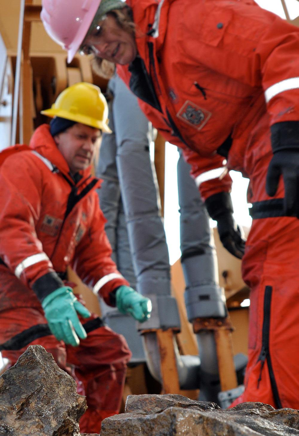 Dr. Alex Andronikov, a geologist from the University of Michigan Department of Geological Science, and Kelley Brumley, a geologist from Stanford University, wear orange jumpsuits, thick gloves and hardhats as they sort through rocks dredged from the Arctic Ocean floor September 9, 2009, aboard the Coast Guard Cutter Healy