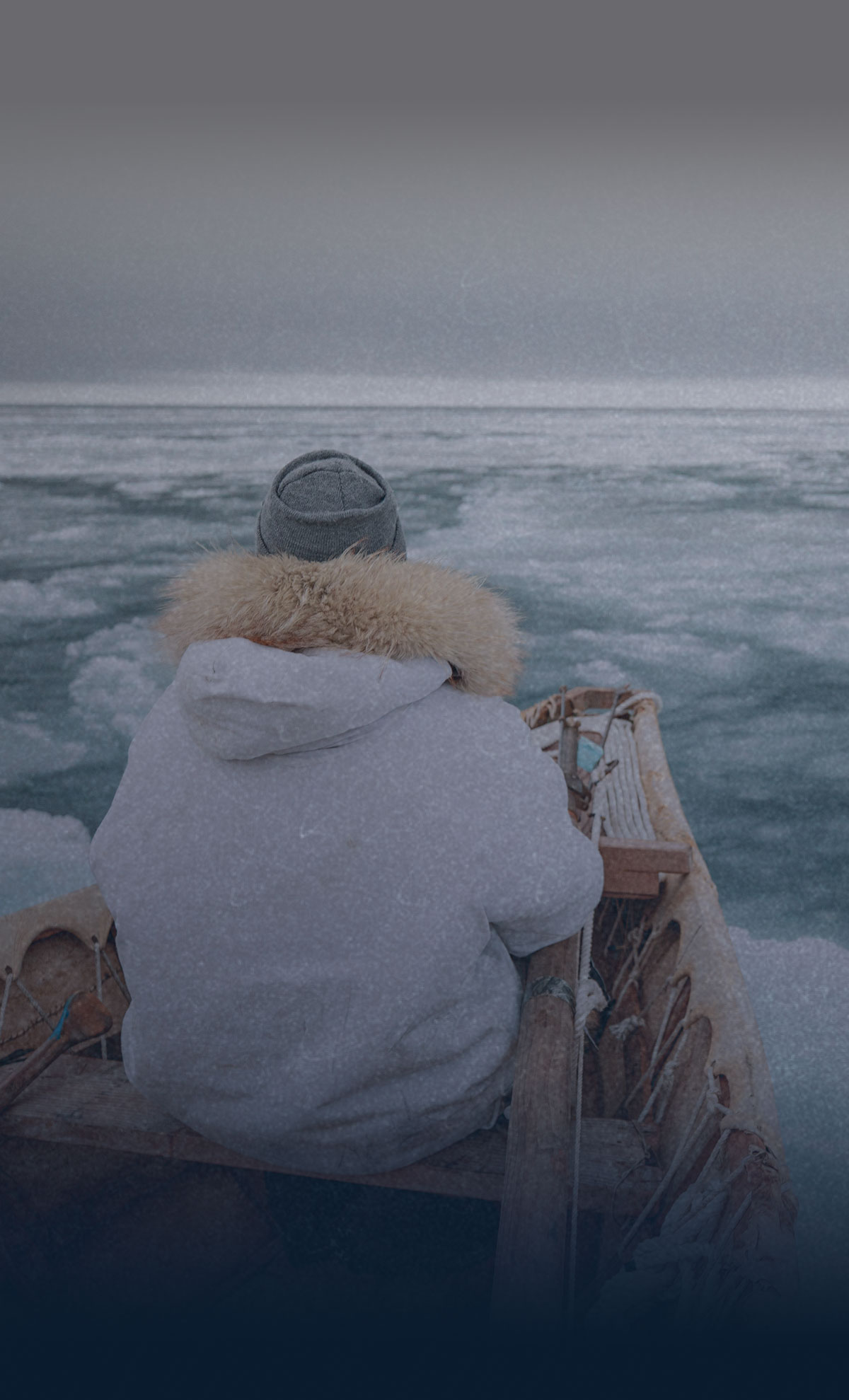 person wearing a coat and hat riding a boat in icy waters