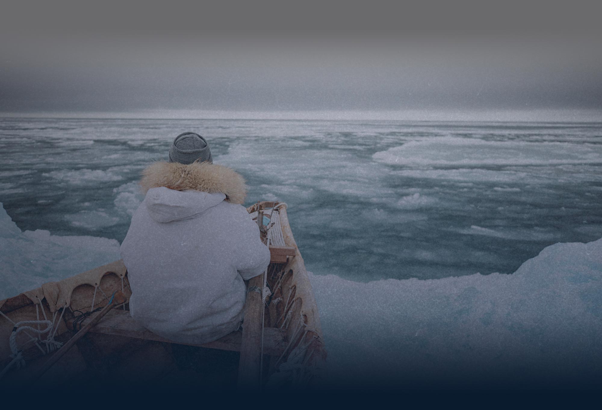 person wearing a coat and hat riding a boat in icy waters