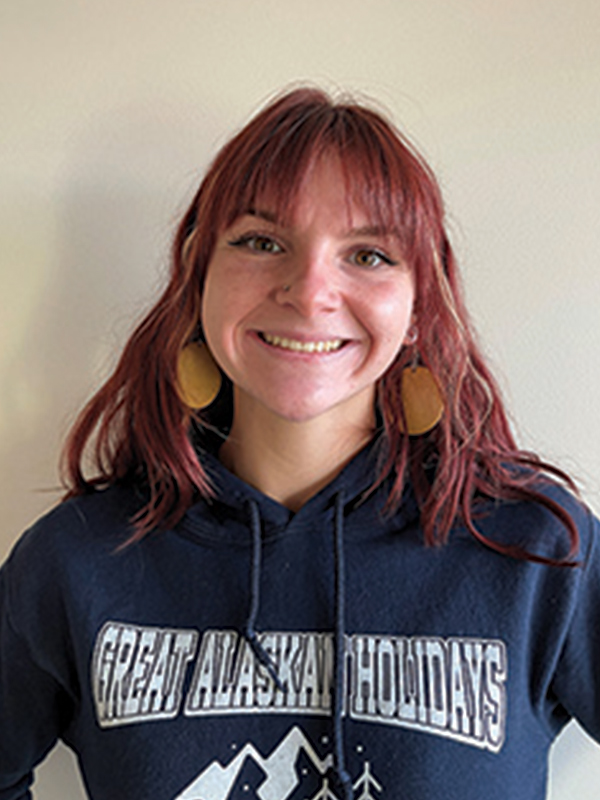 Headshot of a woman with medium red hair, wearing a dark blue sweatshirt